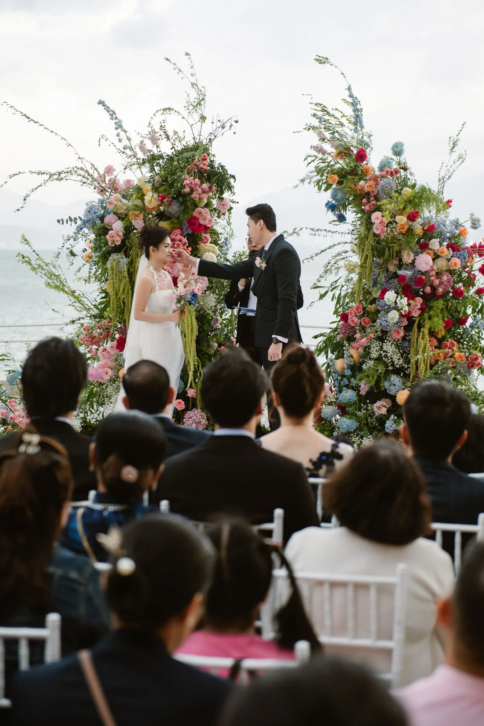Beachfront wedding ceremony with a colourful floral arch overlooking the sea in Nha Trang