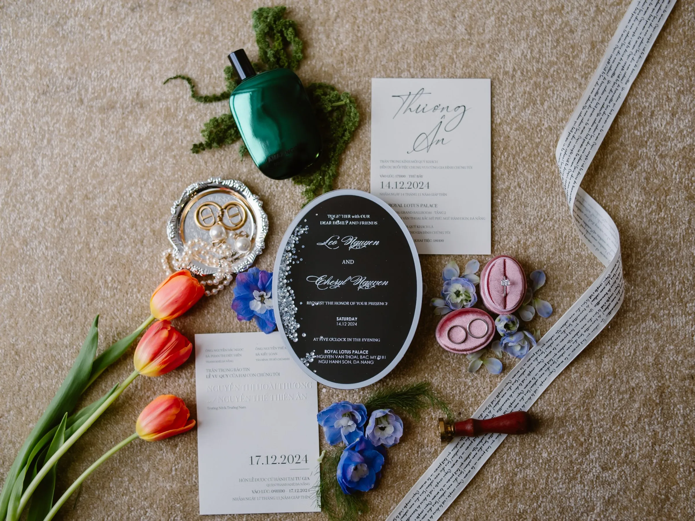 Wedding invitation, rings, perfume and tulips flat-lay at a Da Nang wedding by TIMO Wedding