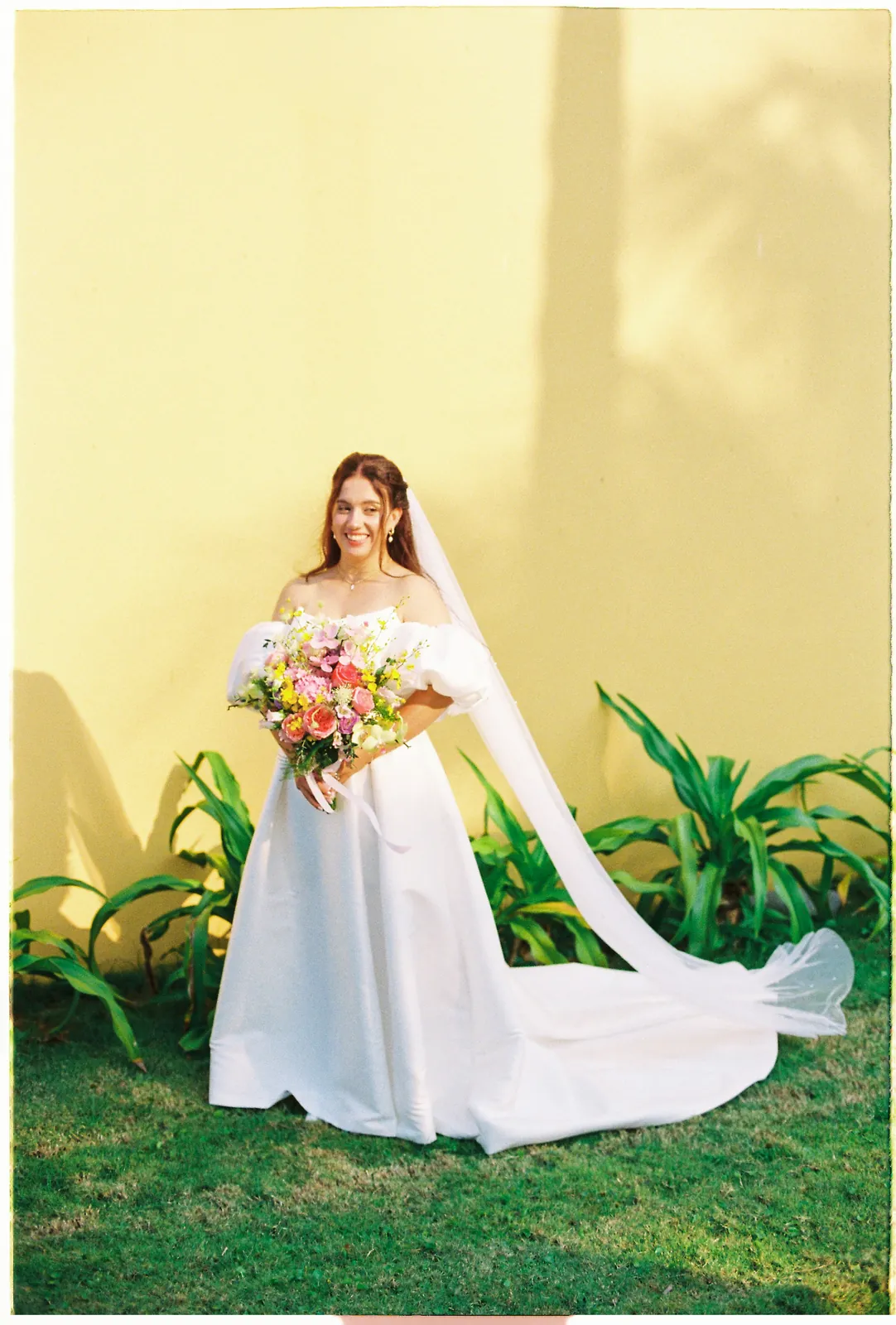 Bride in a film portrait against the yellow colonial walls of Victoria Hoi An Beach Resort, Vietnam