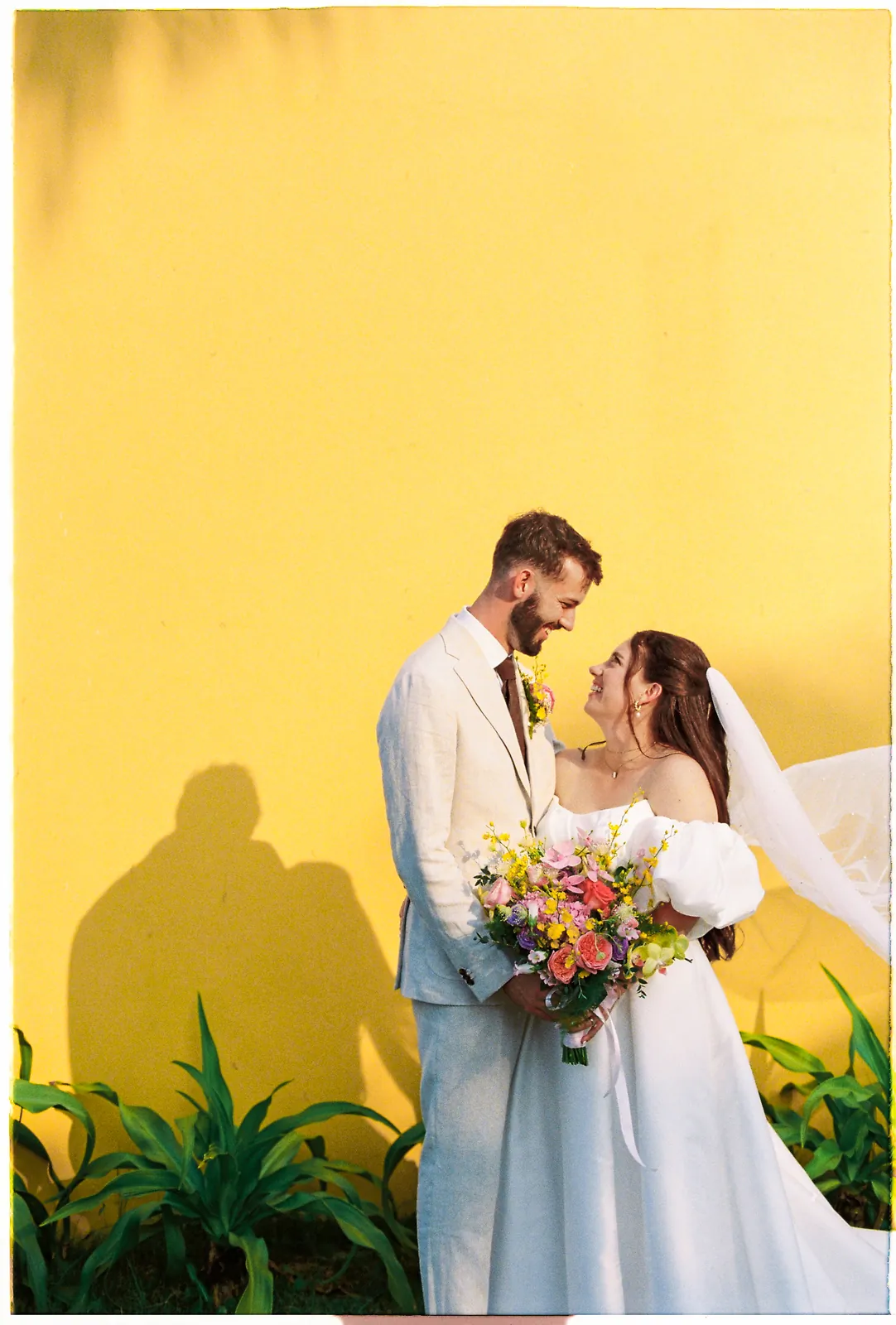 Couple against the yellow colonial walls of Victoria Hoi An, film wedding photography