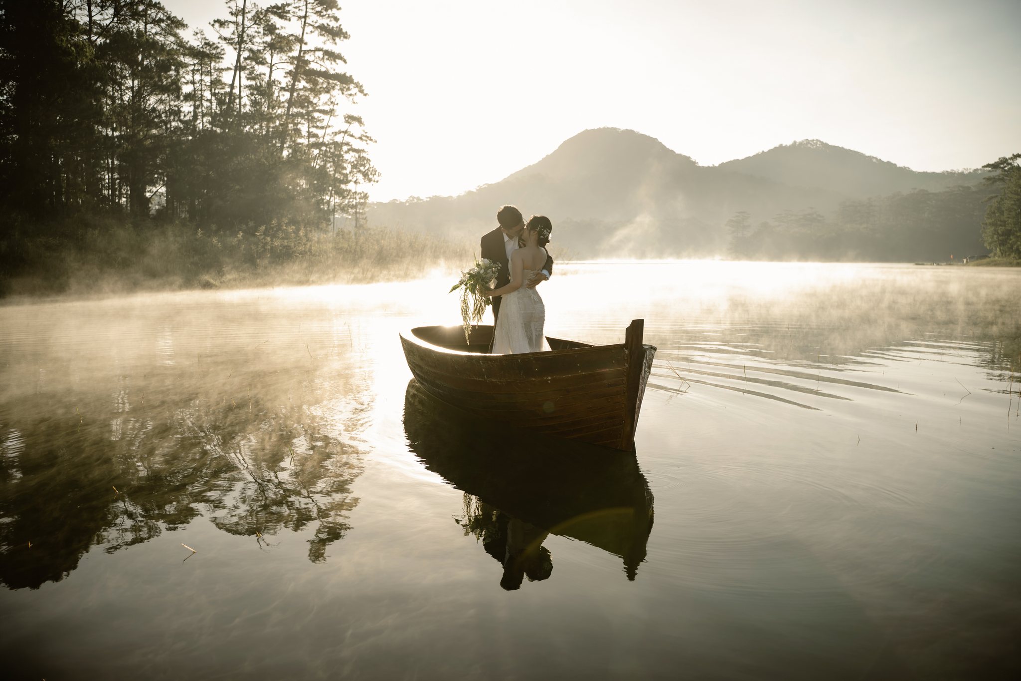 A couple in a boat on a misty Da Lat lake at sunrise