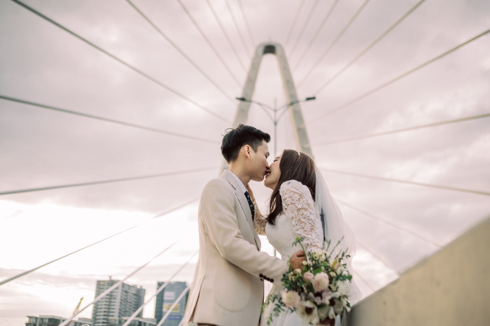 Couple kissing on a bridge with the Ho Chi Minh City skyline behind