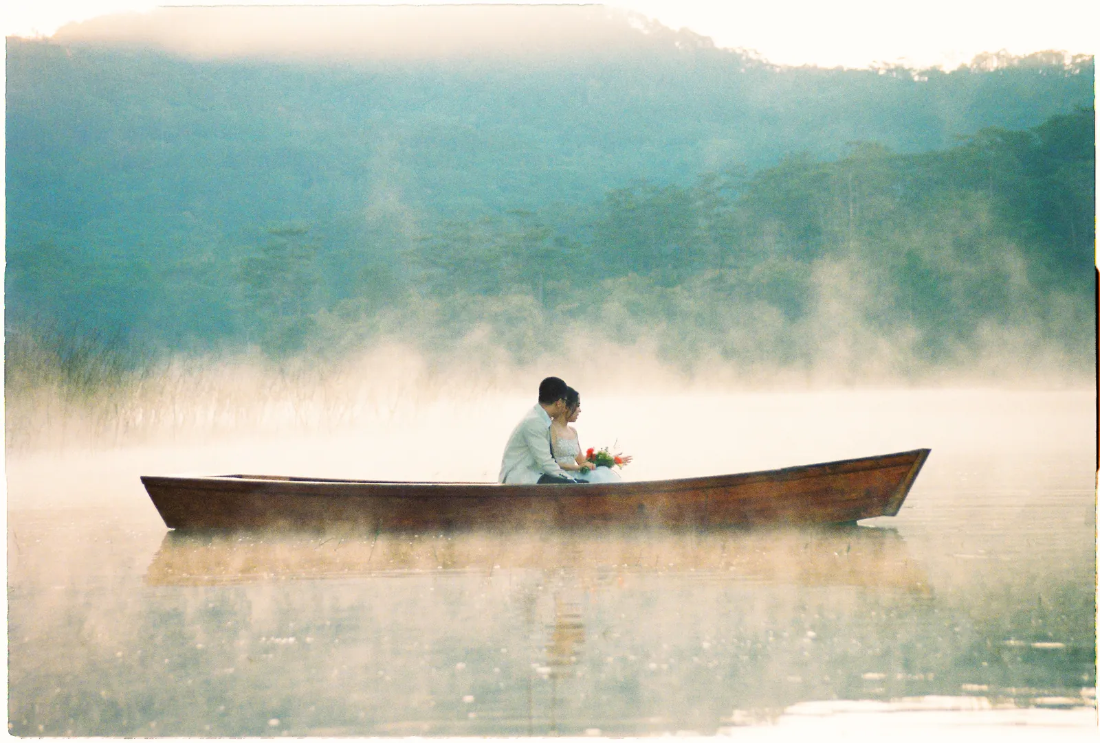 A lone boat on a misty Da Lat lake at dawn