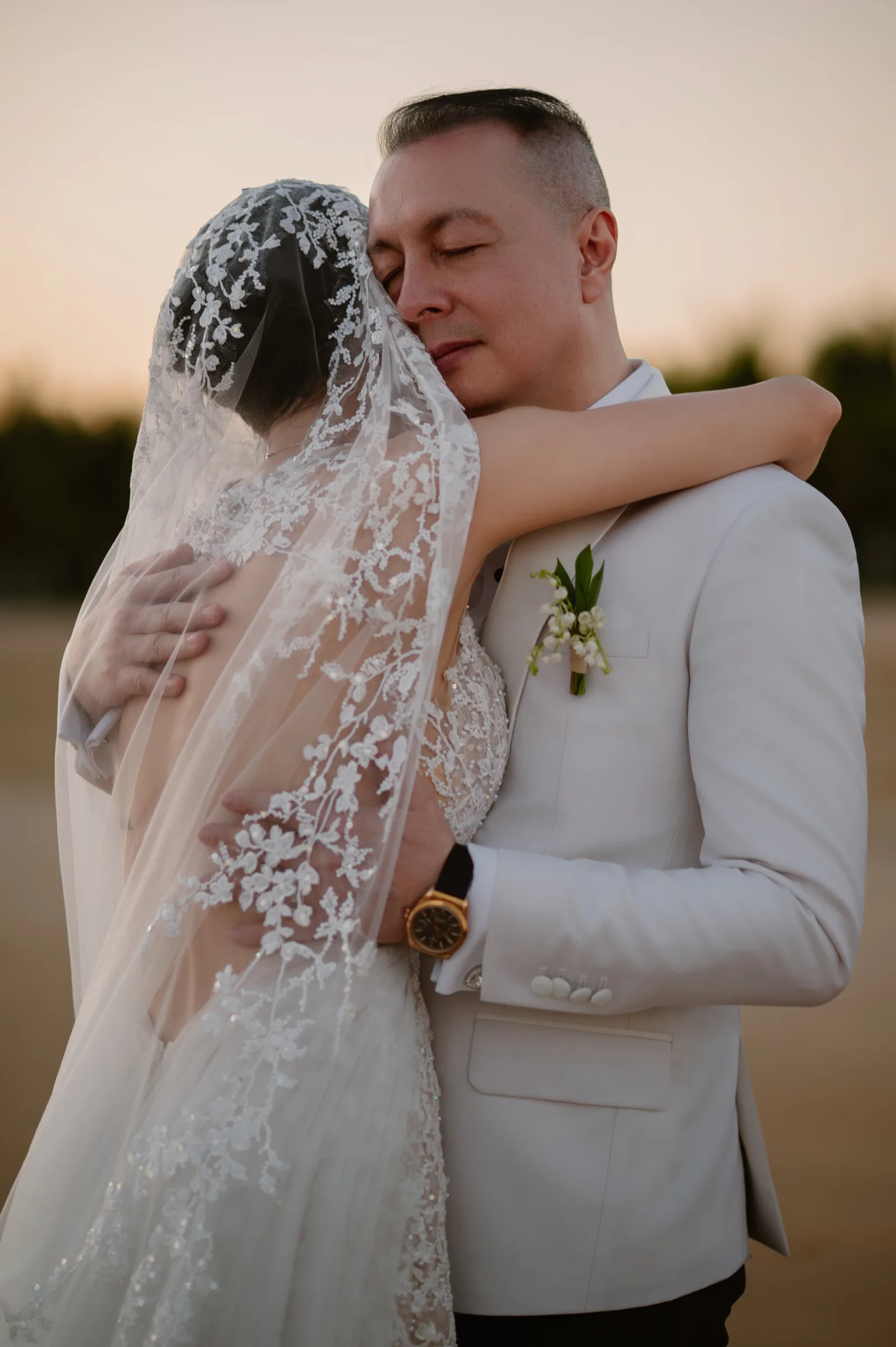 A couple embracing at golden hour on the beach at their Melia Ho Tram wedding by TIMO Wedding