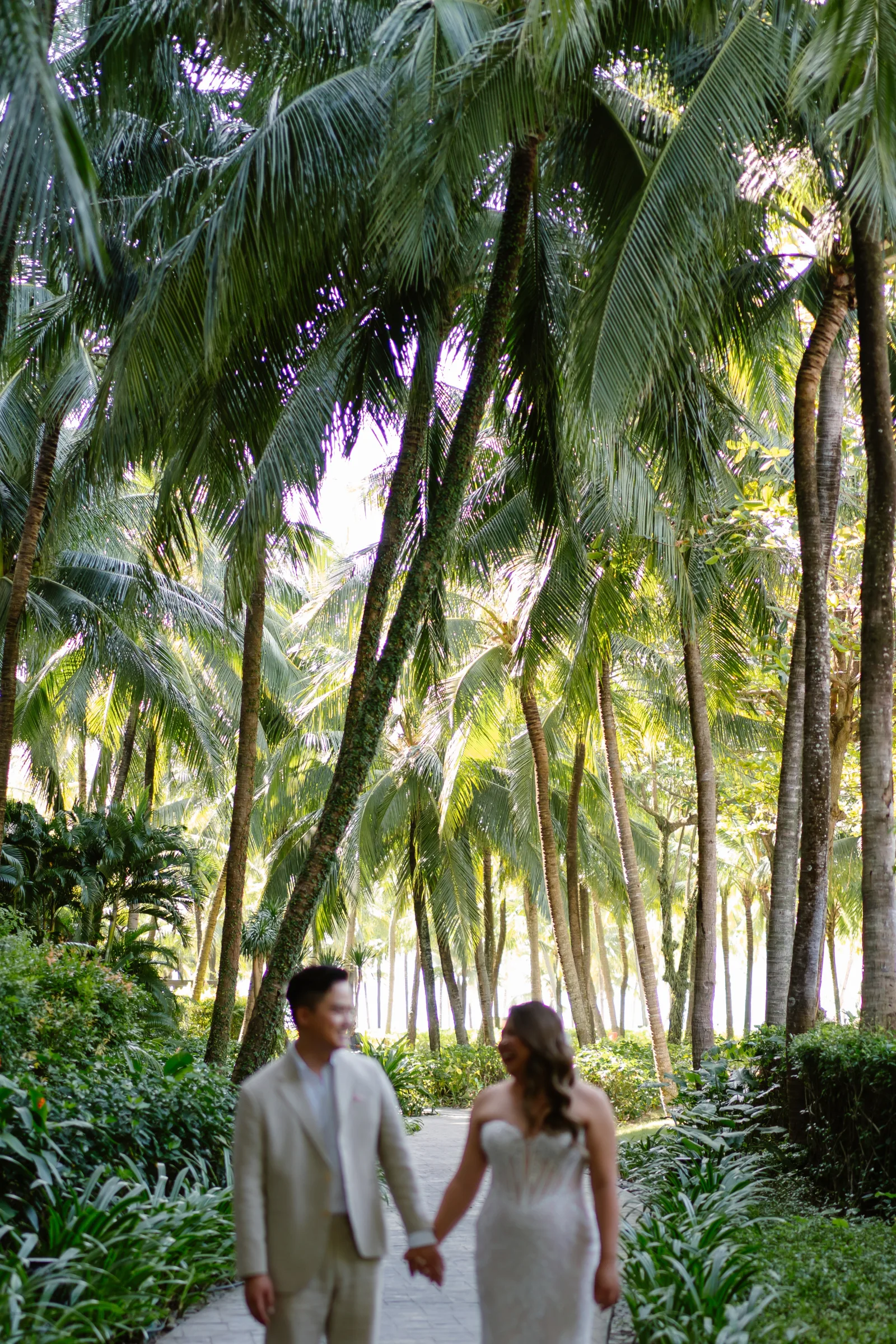 A couple walking hand in hand through the palms at their InterContinental Phu Quoc luxury wedding by TIMO Wedding